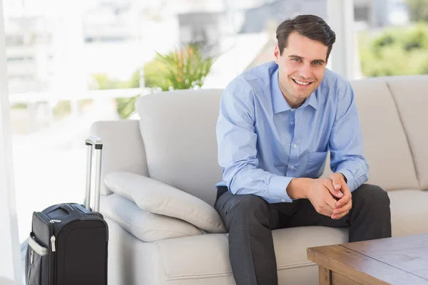 Hombre de negocios sonriente sentado en el sofá esperando salir en busines — Foto de Stock