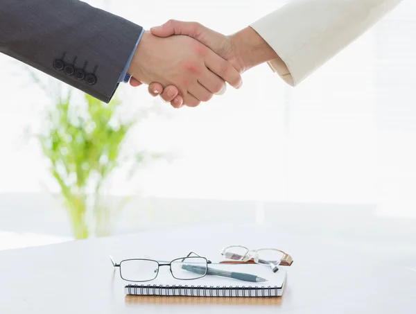 Shaking hands over eye glasses and diary after business meeting — Stock Photo, Image