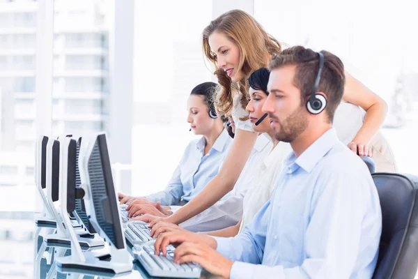 Gerente e executivos com fones de ouvido usando computadores — Fotografia de Stock