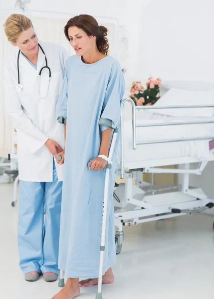 Doctor talking to patient in crutches — Stock Photo, Image