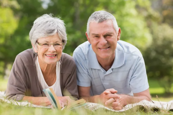 Smiling relaxed senior couple lying in park — Stock Photo, Image
