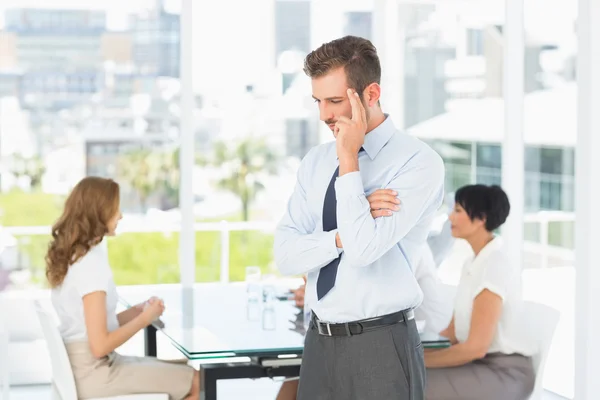 Pensativo hombre de negocios con colegas en la reunión detrás — Foto de Stock