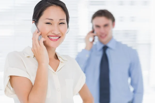 Zakenvrouw en man cellphones gebruiken in office — Stockfoto