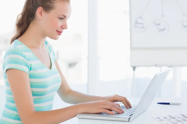 Young casual woman using laptop at office — Stock Photo, Image