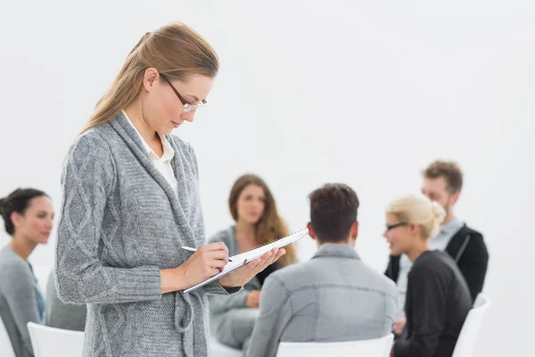 Therapist writing notes with group therapy in session — Stock Photo, Image
