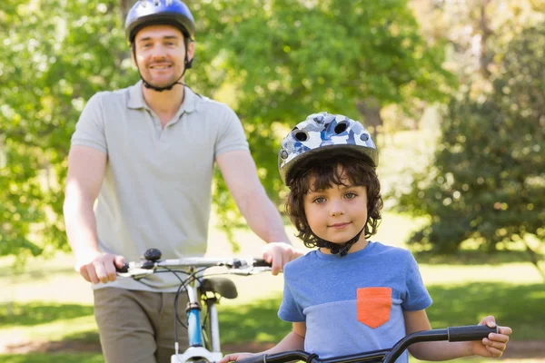 Uomo sorridente con suo figlio in bicicletta — Foto Stock