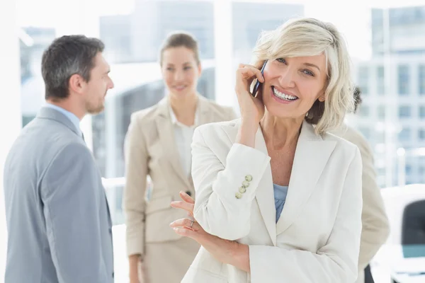 Mature businesswoman on call with colleagues at office — Stock Photo, Image