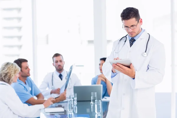 Médico usando tablet digital com colegas em reunião — Fotografia de Stock