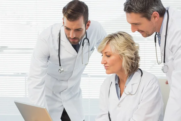 Tre medici concentrati che utilizzano il computer portatile insieme — Foto Stock