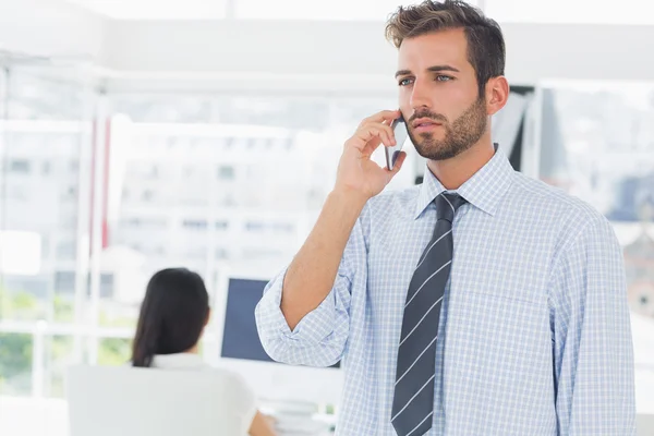 Artista maschile casuale utilizzando il telefono cellulare con il collega nella parte posteriore — Foto Stock