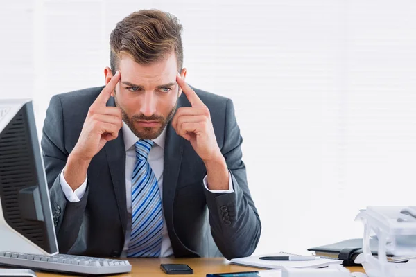 Businessman with severe headache at office desk — Stock Photo, Image