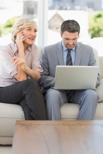 Businesswoman on call while colleague using laptop at home — Stock Photo, Image