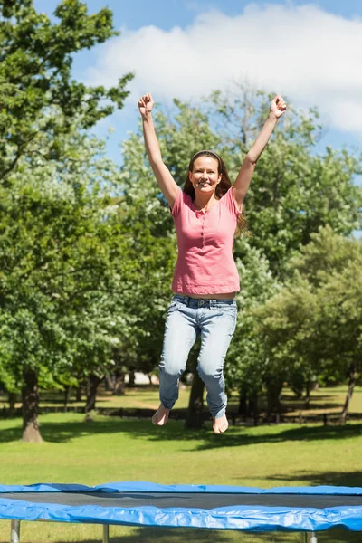 Happy woman jumping high on trampoline in park — Stock Photo, Image