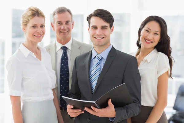 Empresário segurando documento sorrindo para a câmera com sua equipe — Fotografia de Stock