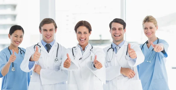 Cheerful doctors gesturing thumbs up at hospital — Stock Photo, Image