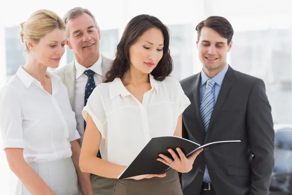 Empresária lendo um documento com sua equipe — Fotografia de Stock