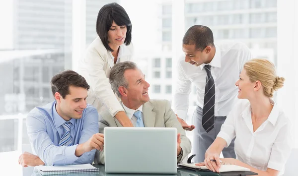 Team di business felice riuniti intorno laptop parlando — Foto Stock