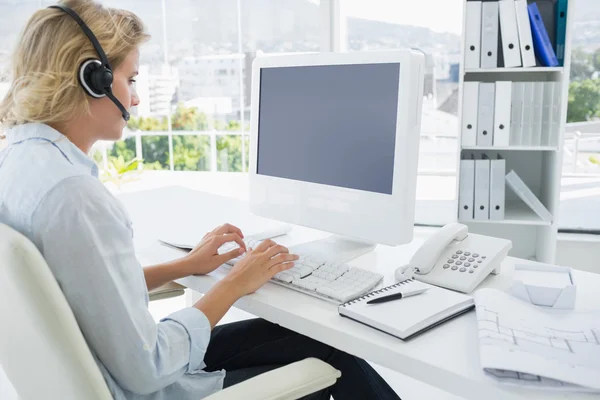 Casual young woman with headset using computer — Stock Photo, Image