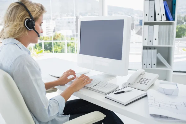 Casual giovane donna con auricolare utilizzando il computer — Foto Stock