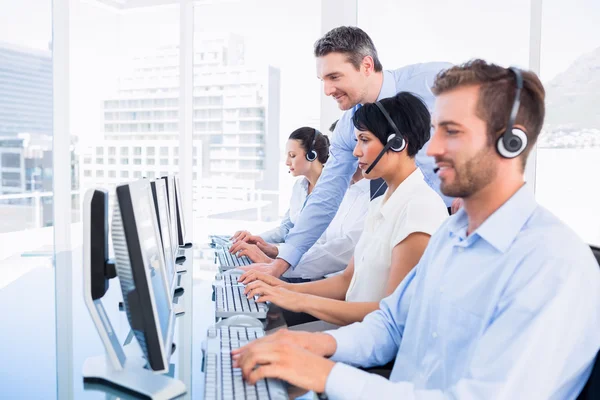 Manager en leidinggevenden met headsets met behulp van computers — Stockfoto