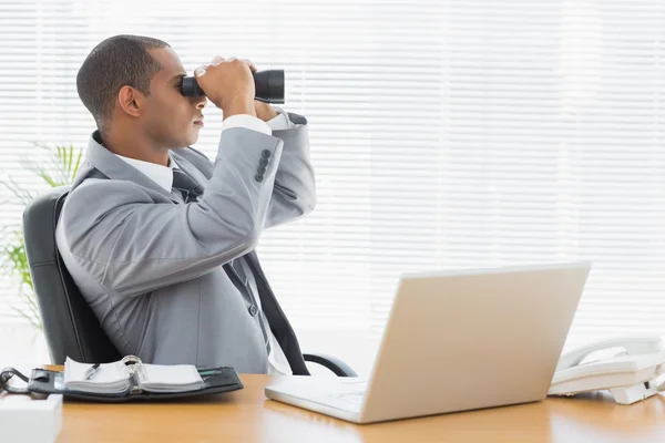 Hombre de negocios mirando a través de prismáticos en el escritorio de la oficina — Foto de Stock