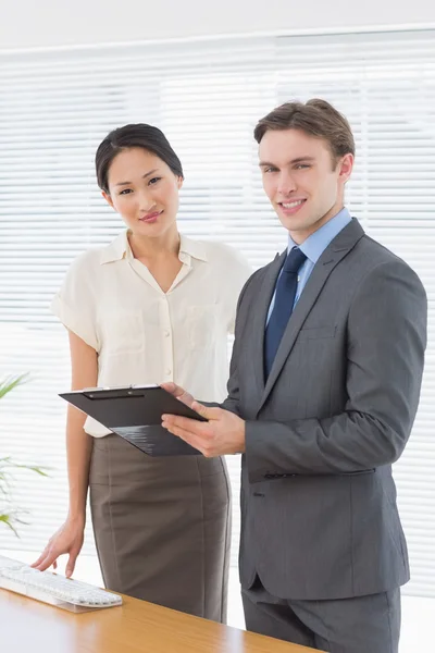 Selbstbewusste Geschäftskollegen mit Klemmbrett im Büro — Stockfoto