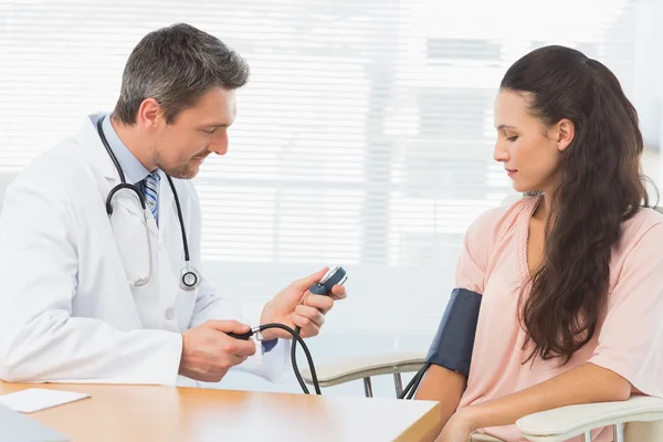 Male doctor checking blood pressure of a woman — Stock Photo, Image
