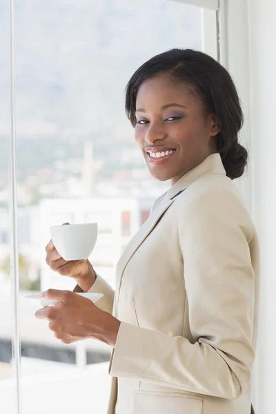 Elegante donna d'affari sorridente con una tazza di tè in ufficio — Foto Stock