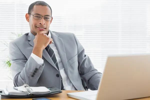 Confident businessman with laptop at office desk — Stock Photo, Image