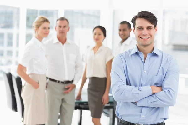 Feliz hombre de negocios de pie con el equipo detrás de él — Foto de Stock