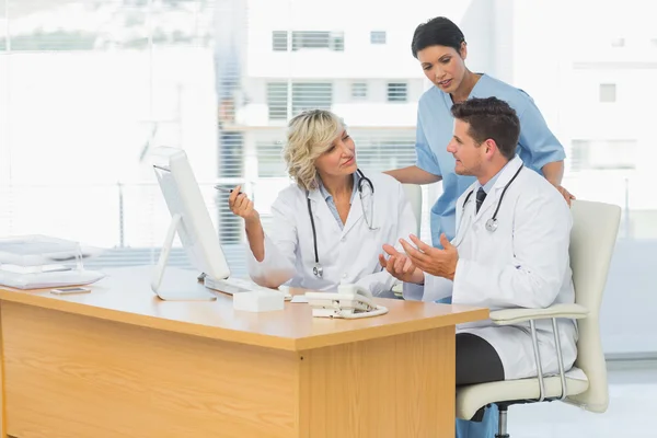 Drie geconcentreerde artsen samen met behulp van computer — Stockfoto