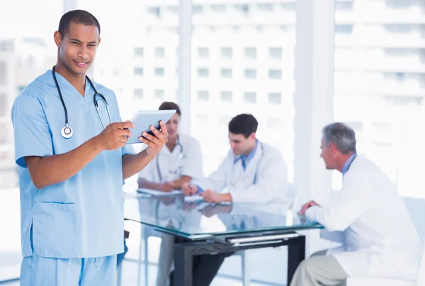 Surgeon using digital tablet with group around table in hospital — Stock Photo, Image