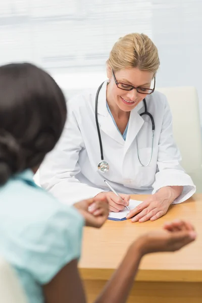 Médico feliz ouvir seu paciente e tomar notas — Fotografia de Stock