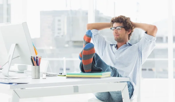 Casual ung man med ben på skrivbord i office — Stockfoto