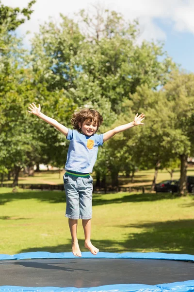 Happy boy jumping high on trampoline in the park — Stock Photo, Image