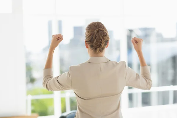Rear of a businesswoman clenching fists in office — Stock Photo, Image