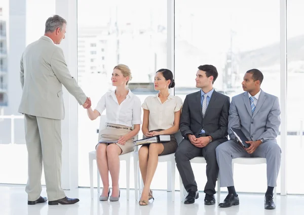 Businessman shaking hands with woman by people waiting for inter — Stock Photo, Image