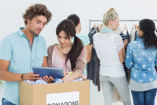 Persone con donazione di vestiti durante l'utilizzo di tablet digitale — Foto Stock