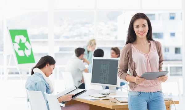 Artista femenina sosteniendo tableta digital con colegas en backgrou —  Fotos de Stock