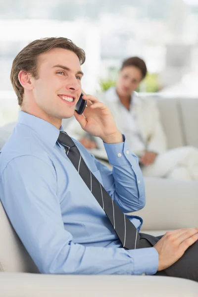 Glad affärsman på telefonen sitter på soffan — Stockfoto