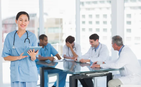 Surgeon using digital tablet with group around table in hospital — Stock Photo, Image