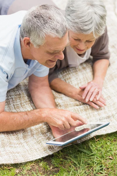 Smiling senior couple using digital tablet at park — Stock Photo, Image