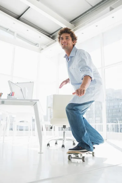 Gelukkig jonge man skateboarden in office — Stockfoto