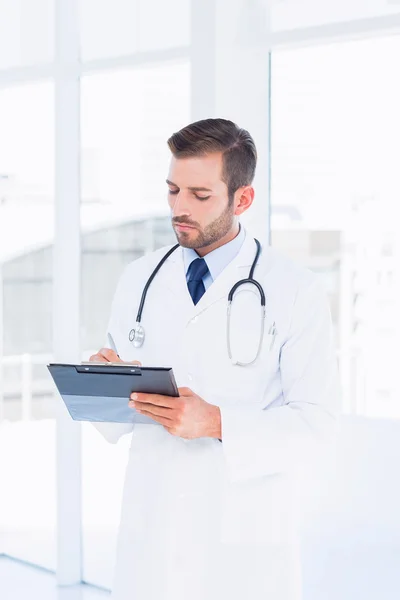 Koncentrerad manliga läkare skriva rapporter i Urklipp — Stockfoto