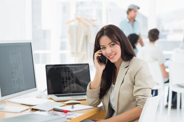 Kvinna på samtal på skrivbord med kollegor bakom i office — Stockfoto