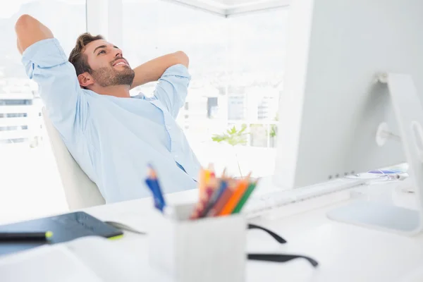 Casual young man resting with hands behind head in office — Stock Photo, Image