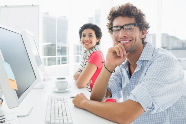 Sonriente pareja casual en el escritorio en la oficina —  Fotos de Stock