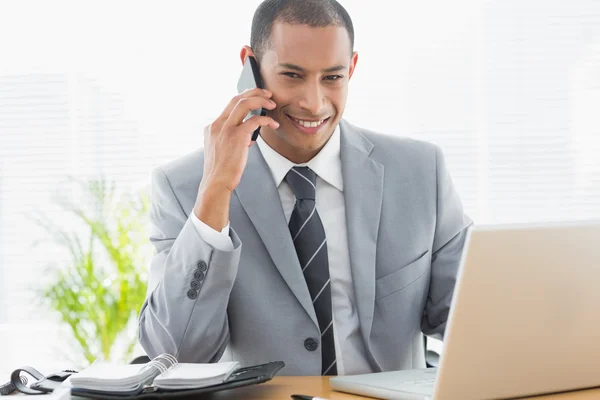 Lachende zakenman met behulp van laptop en mobiele telefoon — Stockfoto