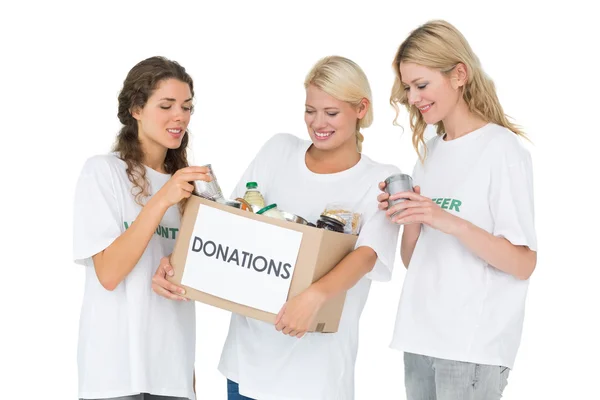 Three smiling young women with donation box — Stock Photo, Image
