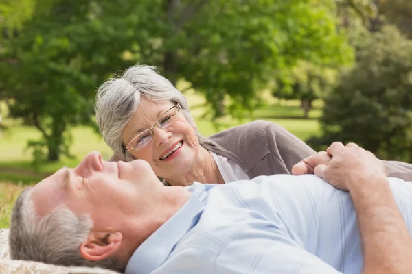 Side of a senior couple lying at park — Stock Photo, Image